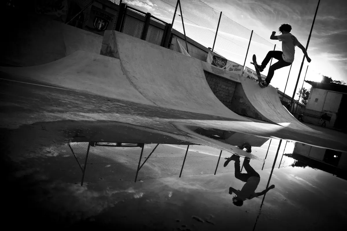 Skating a quarter pipe at the concrete park in Cantù, reflected in a puddle